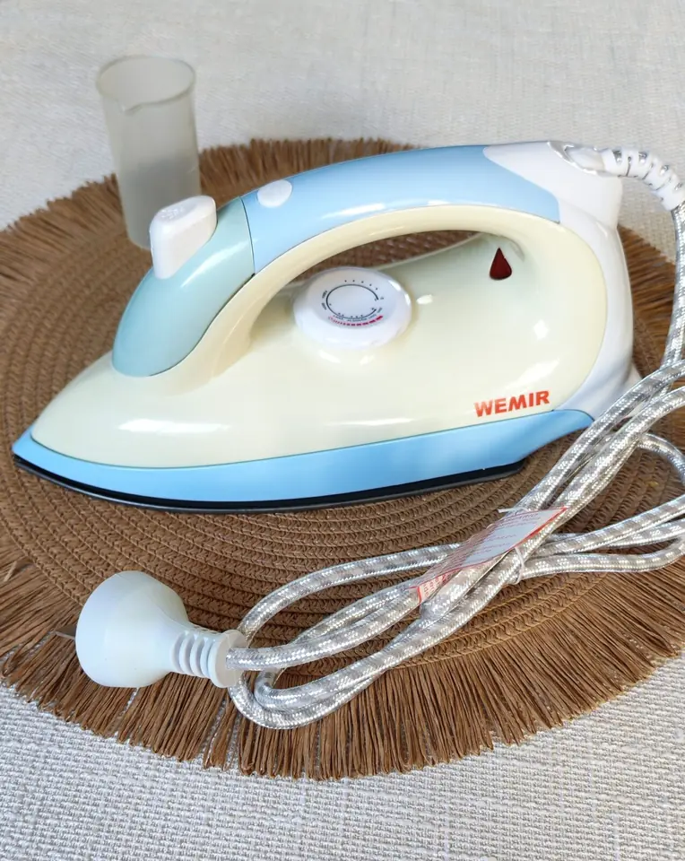 Plancha Wemir de color celeste y blanco, con una base antiadherente de 1200W y función de spray.